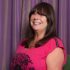 Headshot of Linda Algie who has long dark hair and wears a pink top.