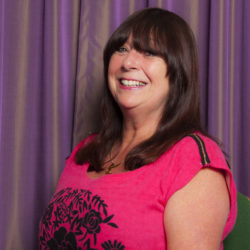 Headshot of Linda Algie who has long dark hair and wears a pink top.