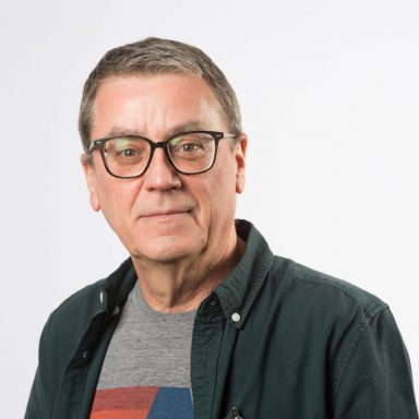 GDA Trustee Billy McFarlane - Billy has glasses and short dark hair, and is wearing a colourful t-shirt under a dark shirt.