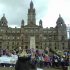 Large group of members sit outside Glasgow City Chambers at a rally
