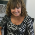 GDA Trustee Nancy Birney in her office chair - Nancy has long curly dark blnde hair and a fringe, and is wearing a black and white patterned top.