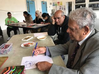 Members sitting at a table, drawing