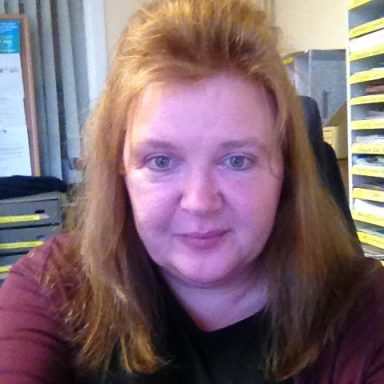 headshot of Angela Mullen who has shoulder length hair and wears a purple top.