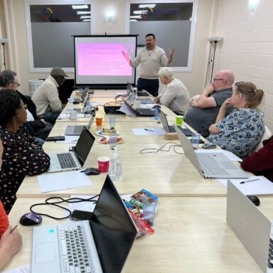 Jonathan stands at the front of the room, delivering digital coaching to a room of GDA members.