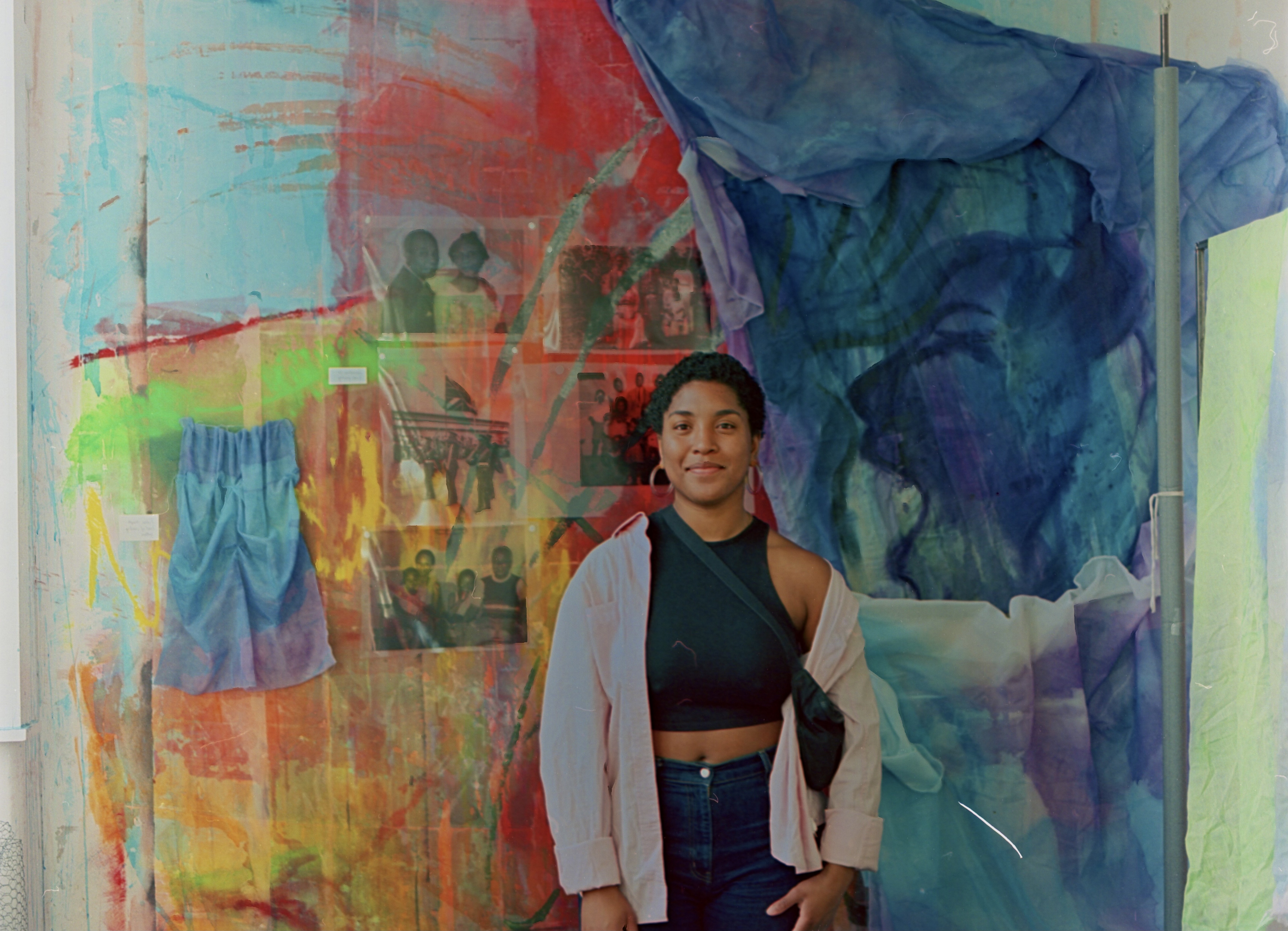 Sai stands in front of a colourful painted background