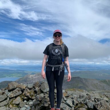 Photo of Rachel standing atop a mountain, surrounded by rocks.